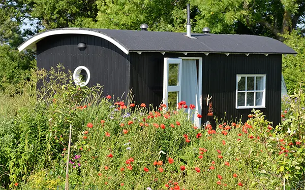 Bauwagen Tiny House in natürlicher Gartenumgebung mit Blumen